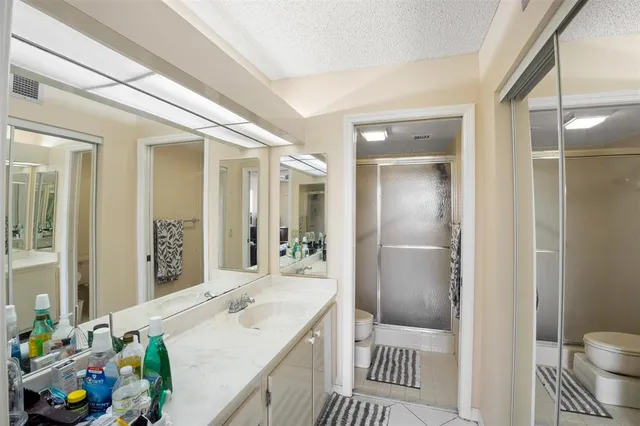 a spacious bathroom with a granite countertop sink a toilet a mirror and shower