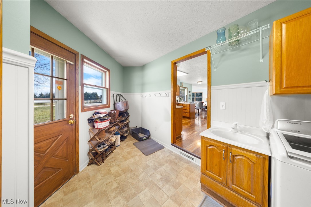 4515 State Road Medina, OH 44256 - Photo 12 of 36 Laundry room featuring a wainscoted wall, washer / dryer, cabinet space, a textured ceiling, and a sink