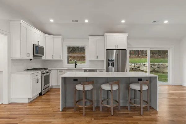 a kitchen with stainless steel appliances granite countertop a stove top oven a sink dishwasher and a refrigerator with wooden floor
