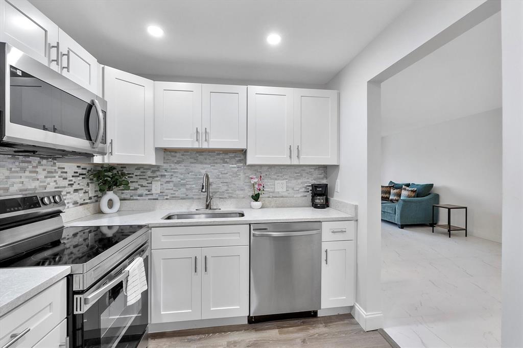 2840 Somerset Drive, Unit 205M Lauderdale Lakes, FL 33311 - Photo 12 of 22 a kitchen with stainless steel appliances granite countertop a sink stove a microwave and cabinets