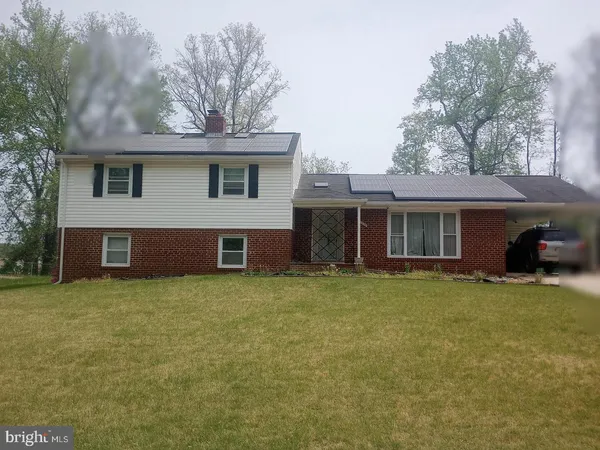 a front view of house with yard and trees in the background