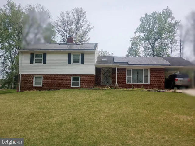 a front view of house with yard and trees in the background
