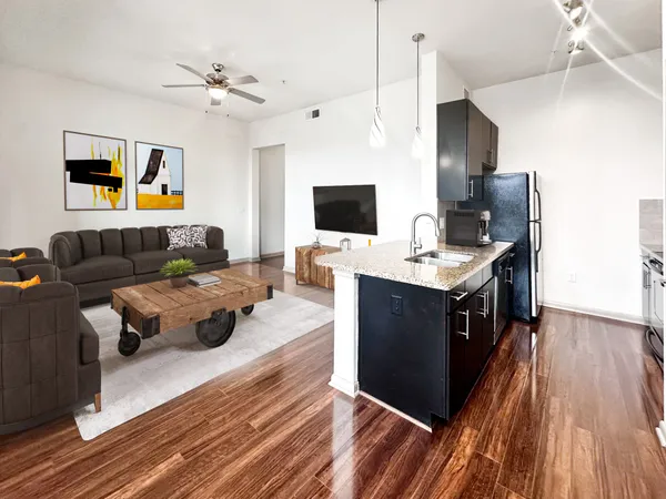 a living room with couches and kitchen view with wooden floor