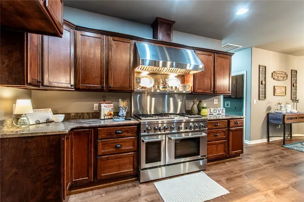 a kitchen with stainless steel appliances granite countertop a stove and a wooden cabinets