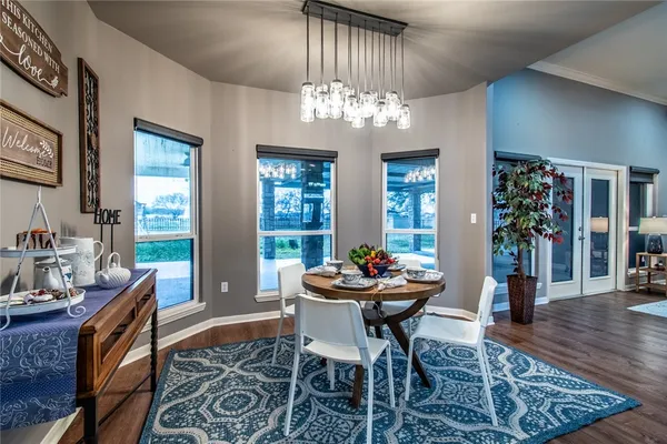 a dining room with wooden floor a chandelier a wooden table and chairs