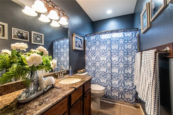 a bathroom with a granite countertop sink a toilet and a mirror