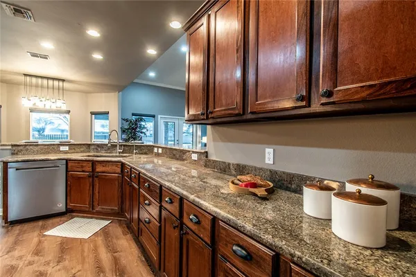 a kitchen with granite countertop stainless steel appliances a sink stove and cabinets