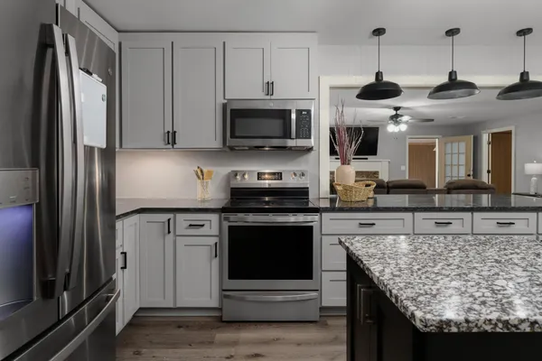 a kitchen with stainless steel appliances granite countertop a stove refrigerator and microwave