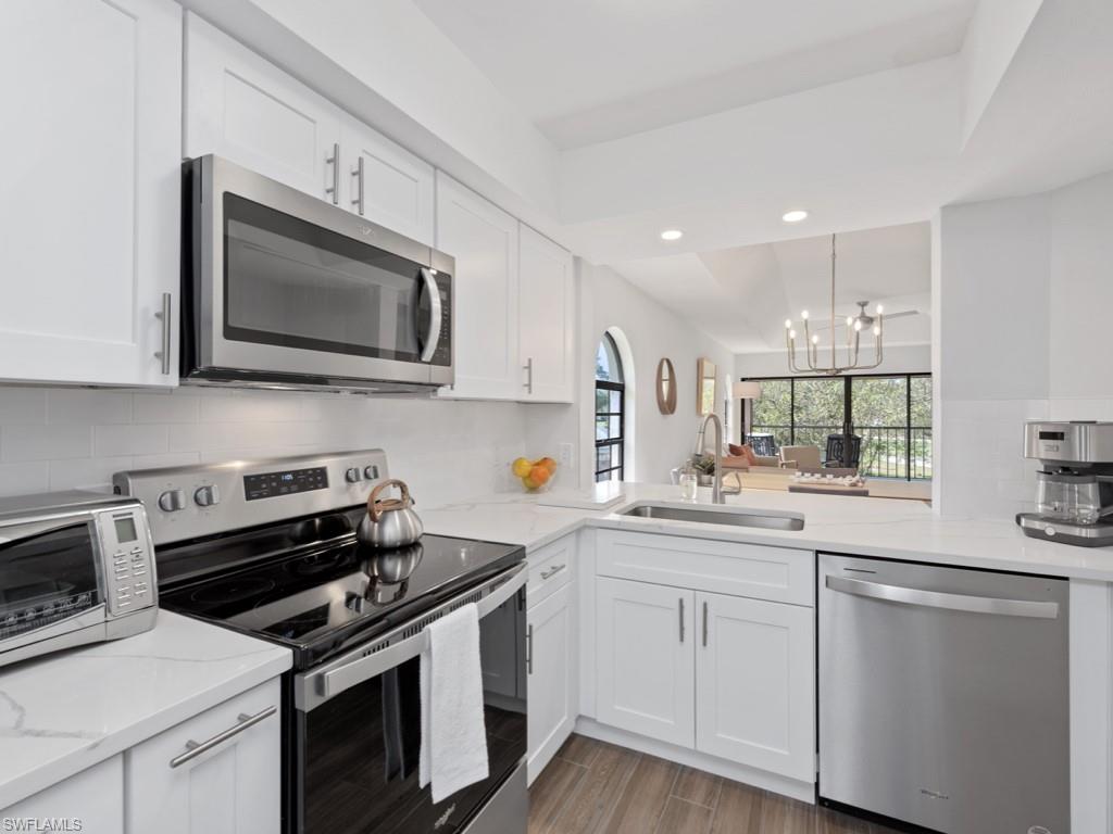 709 Augusta Boulevard, Unit 7095 Naples, FL 34113 - Photo 6 of 16 Kitchen featuring stainless steel appliances, white cabinets, tasteful backsplash, and sink