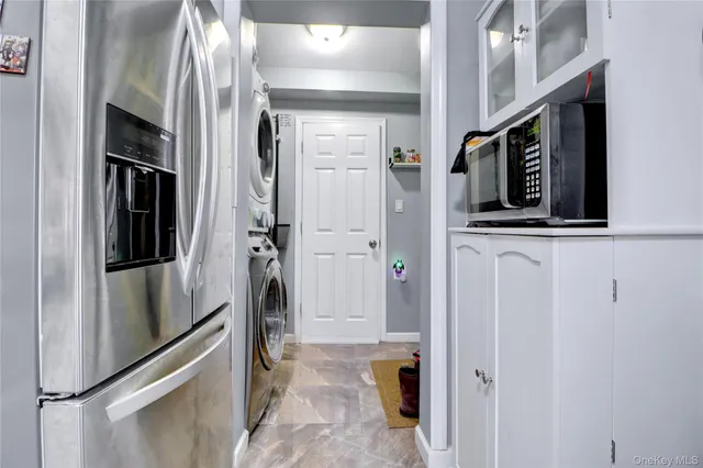 a view of a hallway with wooden cabinets and refrigerator
