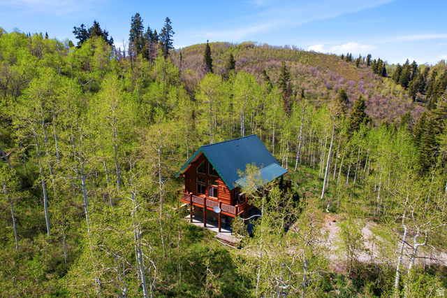 2096 South Aspen Ridge Coalville, UT 84017 - Photo 5 of 44 Log cabin residence featuring a dark green metal roof, multiple windows, and a surrounding forest setting