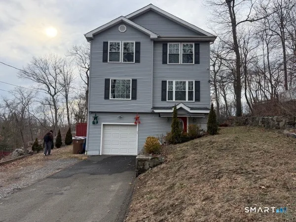 a view of a house with a yard and large tree