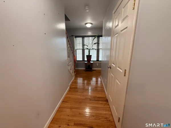 a view of a hallway with wooden floor and a bathroom