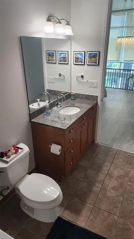 a bathroom with a granite countertop toilet sink and mirror