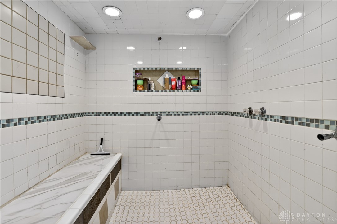 7045-7049 Montgomery Road Cincinnati, OH 45236 - Photo 36 of 68 This tiled shower features a built-in shelf and a stylish mosaic accent, combining functionality with aesthetic appeal.