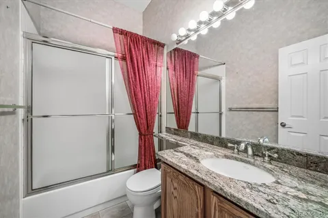 a bathroom with a granite countertop sink toilet and shower