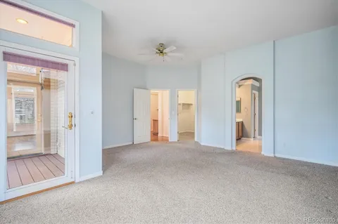 an empty room with windows and ceiling fan