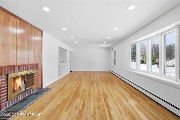 a view of an empty room with wooden floor and a window
