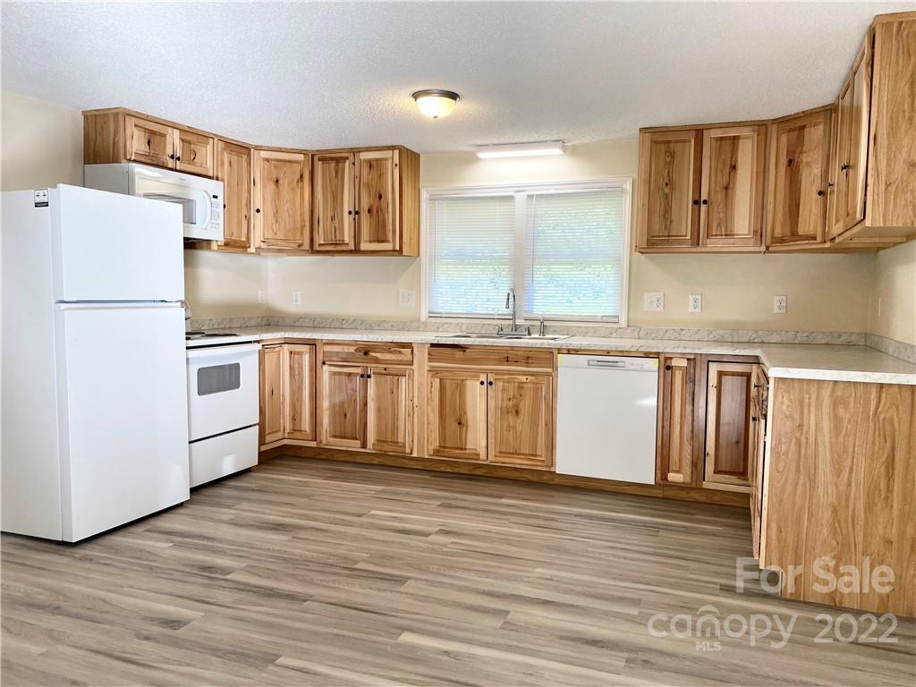 3367 Deerbrook Road Lenoir, NC 28645 - Photo 6 of 13 a kitchen with stainless steel appliances granite countertop a refrigerator a stove a sink and white cabinets with wooden floor