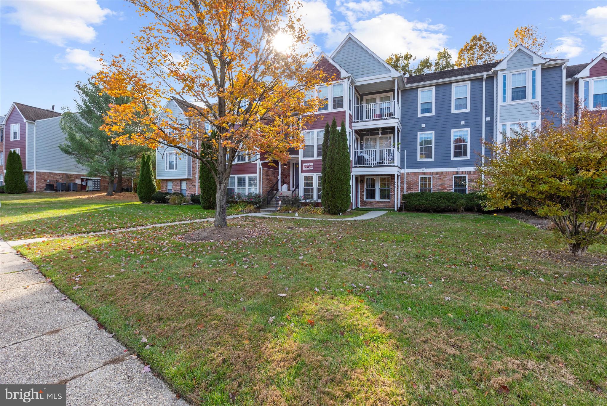 679 Deering Road, Unit 4D Pasadena, MD 21122 - Photo 2 of 28 a view of a brick building next to a big yard and large trees