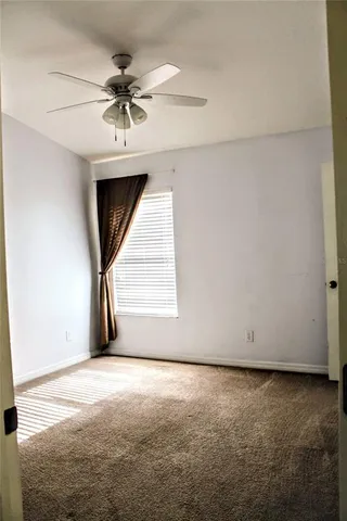 an empty room with a ceiling fan and window