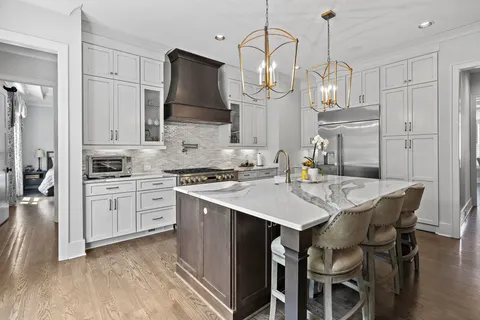 a kitchen with stainless steel appliances granite countertop a sink a stove a refrigerator and island with wooden floor