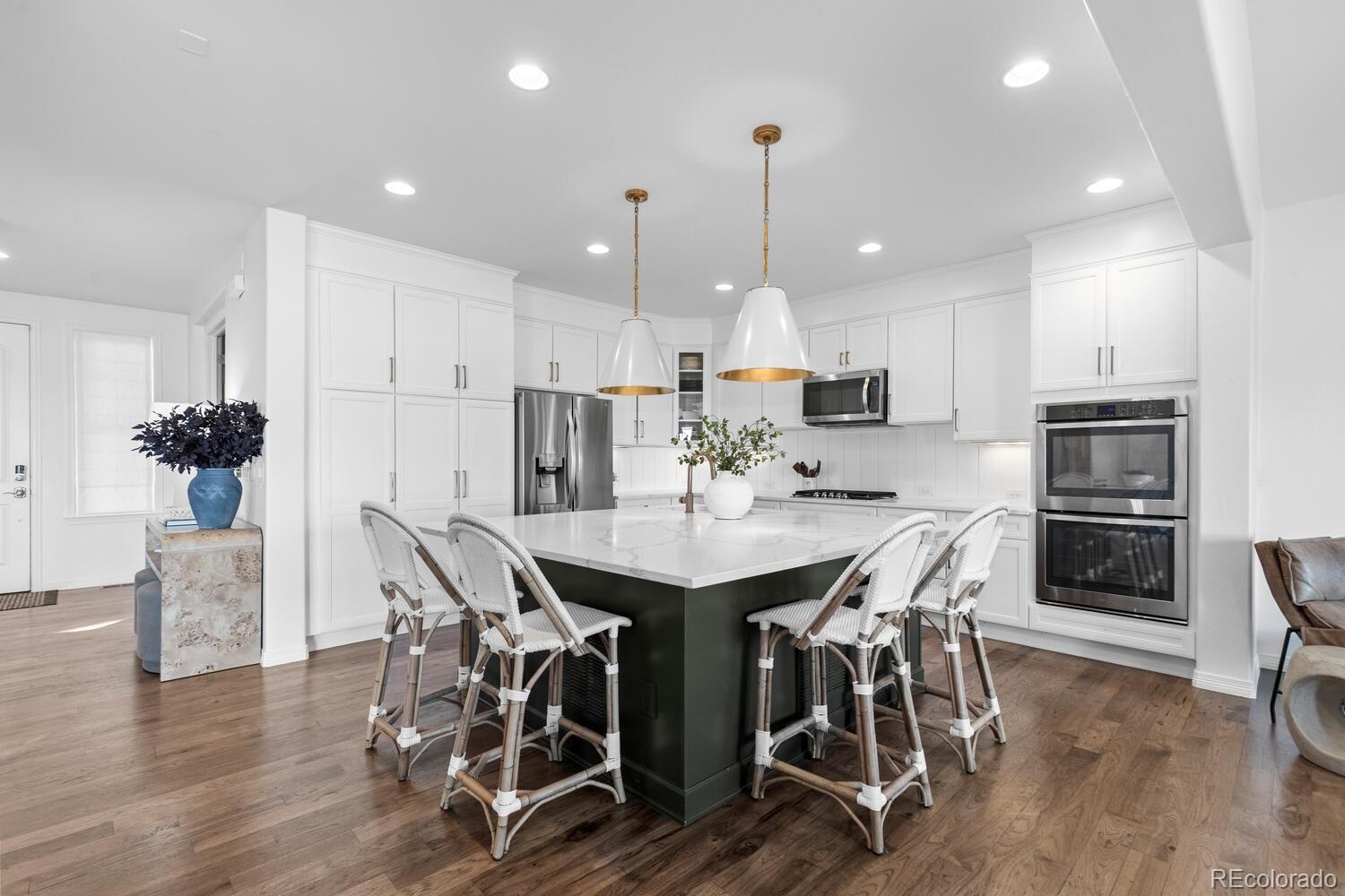 10699 Timberdash Avenue Highlands Ranch, CO 80126 - Photo 7 of 50 a kitchen with stainless steel appliances kitchen island granite countertop a dining table chairs and refrigerator
