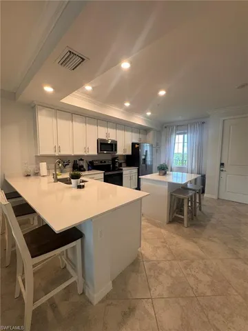 a kitchen with stainless steel appliances granite countertop a table chairs and a refrigerator