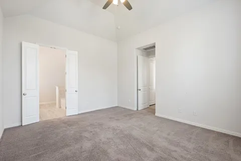 a view of an empty room and chandelier fan