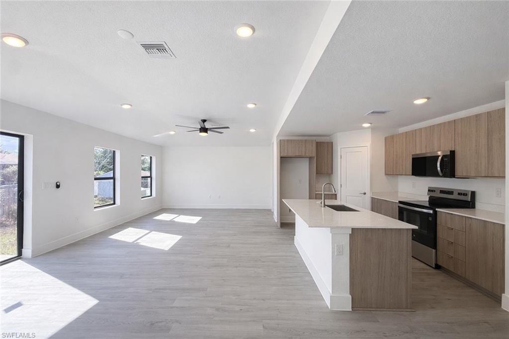 2709 22nd Street Southwest Lehigh Acres, FL 33976 - Photo 17 of 18 a large kitchen with stainless steel appliances kitchen island a large counter top a sink and a stove