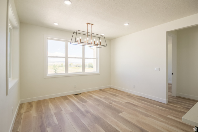 3322 250 S Street Vernal, UT 84078 - Photo 9 of 37 Spacious room featuring wood-finish flooring and a contemporary linear chandelier with exposed bulbs