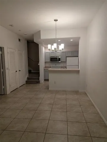 a room with a chandelier and kitchen view
