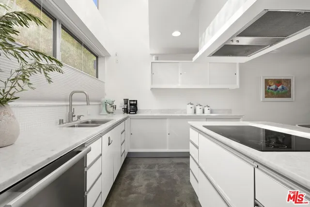a kitchen with a sink dishwasher a stove and white cabinets with wooden floor
