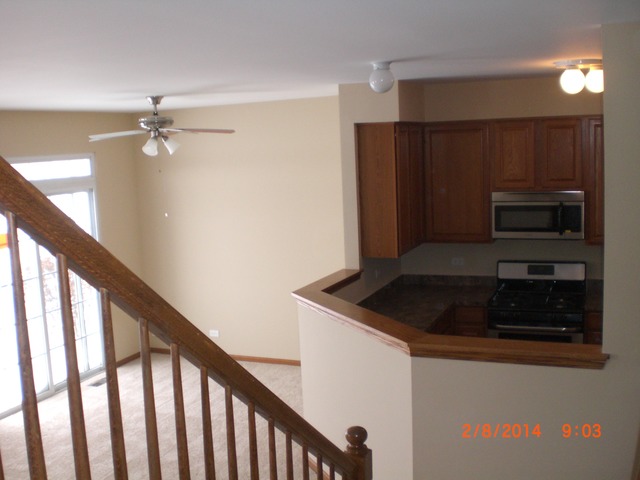 1974 West Cobblestone Road, Unit 3532303 Romeoville, IL 60446 - Photo 9 of 23 a kitchen with kitchen island a stove and a refrigerator with wooden floor