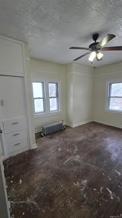 an empty room with windows and fan