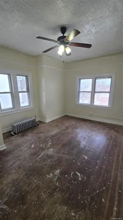en empty room with windows and chandelier fan