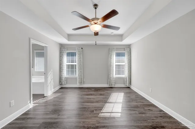 a view of an empty room with window and wooden floor