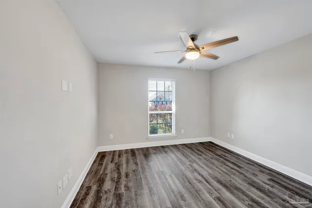 an empty room with wooden floor ceiling fan and window
