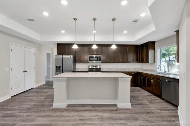 a large white kitchen with a large island oven a sink stainless steel appliances and cabinets