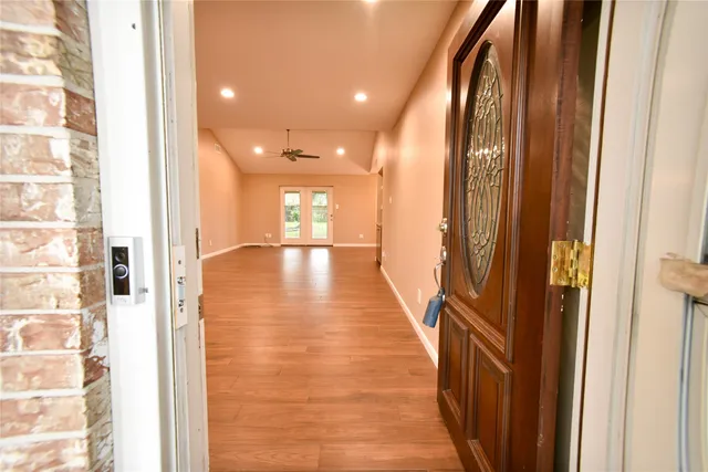 a view of an empty room with wooden floor and a window
