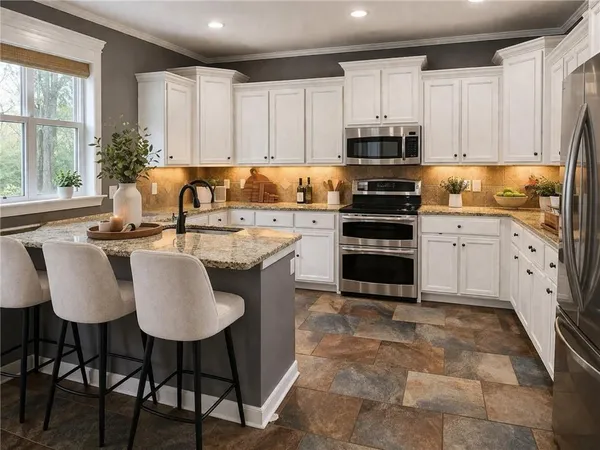 a kitchen with stainless steel appliances a stove a sink a microwave a refrigerator and white cabinets