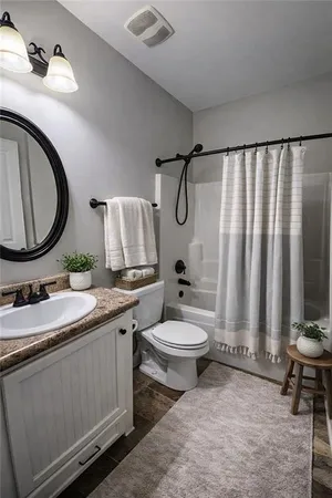a bathroom with a granite countertop toilet sink and mirror