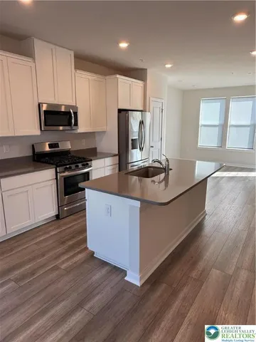 a kitchen with kitchen island granite countertop a sink stove and wooden floor
