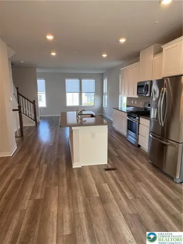 a kitchen with stainless steel appliances granite countertop a sink a stove a refrigerator and cabinets