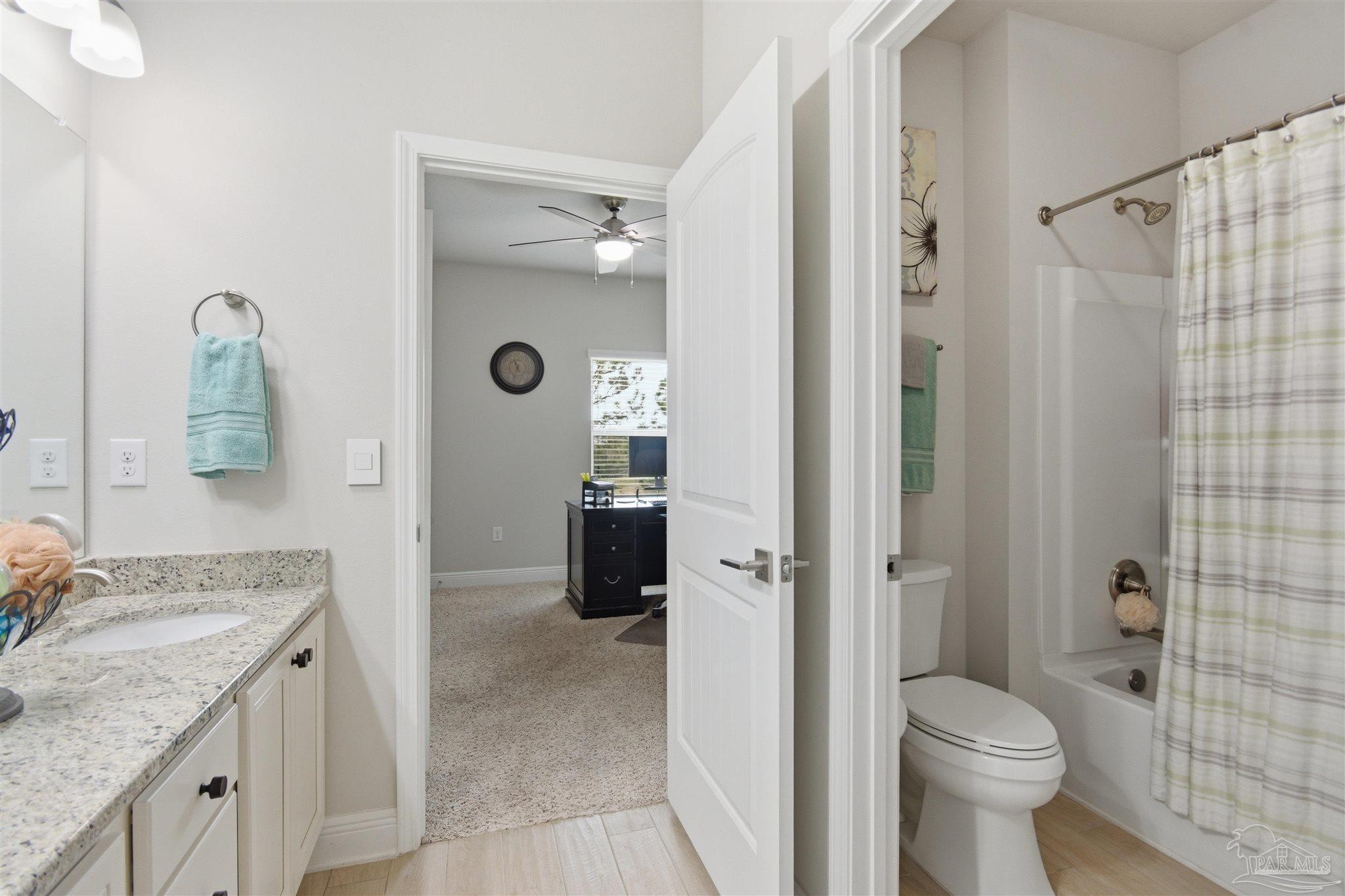 2677 Tulip Hill Road Pace, FL 32571 - Photo 28 of 35 a bathroom with a granite countertop toilet a sink and a shower