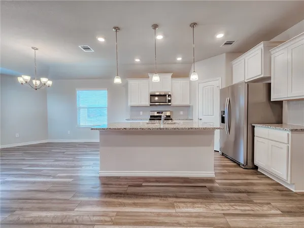 a view of a kitchen with kitchen island a counter top stainless steel appliances and cabinets