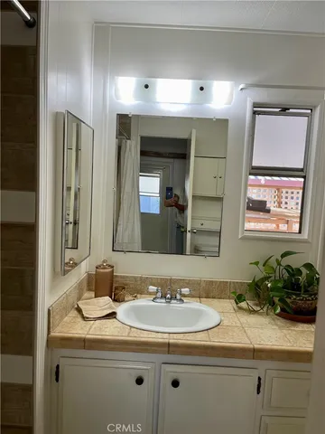 a bathroom with a granite countertop sink a large mirror a and a window