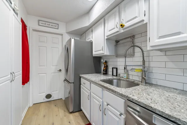 a kitchen with stainless steel appliances granite countertop a sink and refrigerator