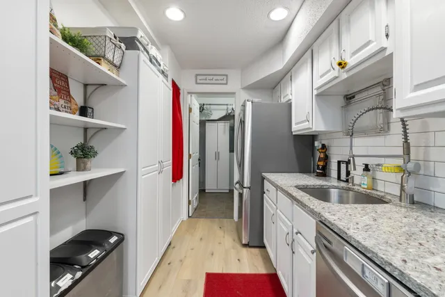 a kitchen with stainless steel appliances granite countertop a sink and a refrigerator