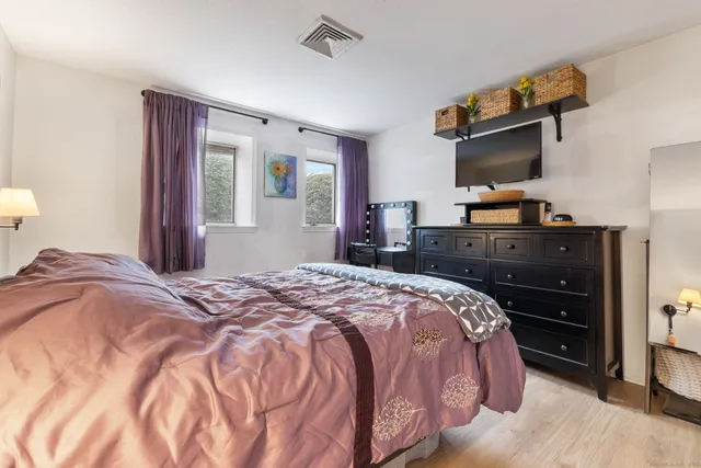 a bedroom with a bed and a flat tv screen on dresser